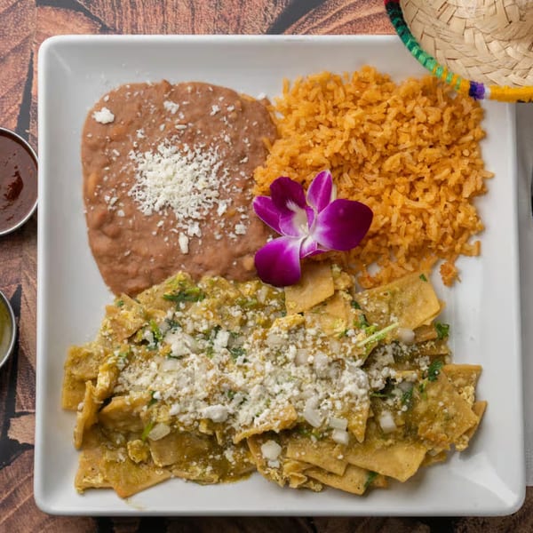 Pueblita Mexican Restaurant's chilaquiles with green sauce, rice, refried beans, and a purple orchid.