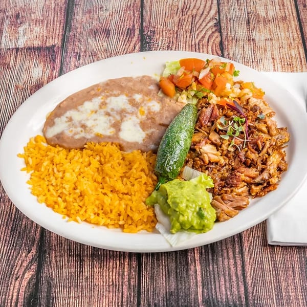 Pueblita Mexican Restaurant's plate with rice, refried beans, shredded chicken, guacamole, salsa, and a jalapeño.
