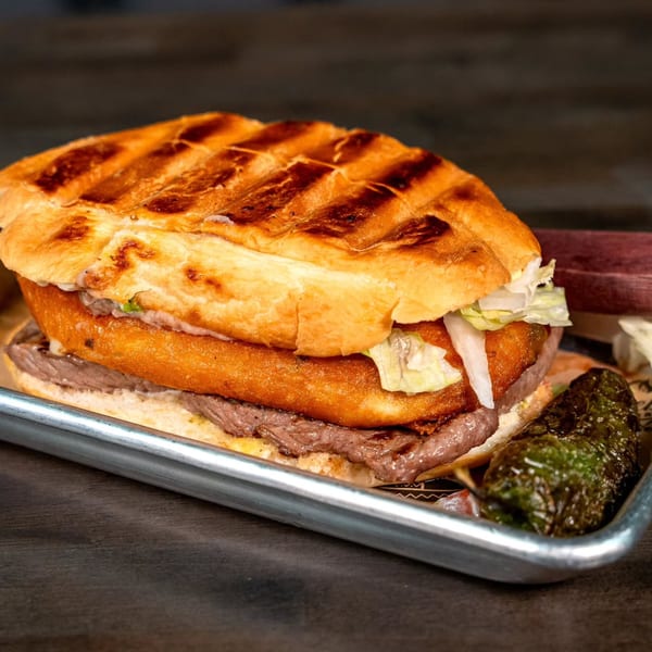 A Pueblita Mexican Restaurant torta with grilled bread, steak, fried cheese, lettuce, and a grilled pepper.